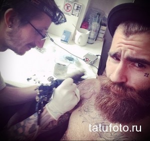 Фото процесса татуировки на лице мужчины: мастер делает татуировку, клиент смотрит в зеркало. Реалистичное фото тату.