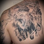 татуировка лев в короне и боевое знамя на лопатке мужчины