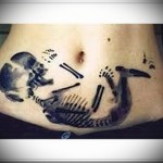 татуировка на животе девушки с скелетом ребенка