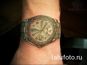 Фото татуировки с реалистичным изображением часов Rolex на запястье. Детализированный рисунок с точной передачей циферблата и браслета.