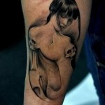 татуировка на запястье с обнаженной девушкой и черепами