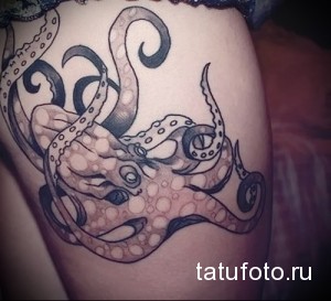 Фото тату: детальная черно-серая татуировка осьминога, обвивающего бедро. Изображение выполнено в реалистичном стиле с акцентом на текстуру кожи и щупальца.