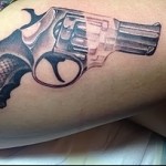 татуировка револьвер на боку правой ноги девушки - фото