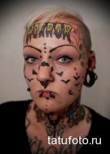 Фотография татуировки на лице женщины: рисунки летучих мышей, надпись "HorrorPop" и другие элементы в стиле хоррор.