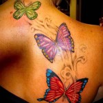три цветные бабочки в полете тату на спине женская