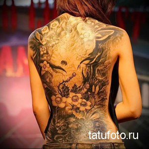 Фото тату: большая и детализированная татуировка на спине, изображающая цветы, дракона и другие мифологические элементы. Черно-серый рисунок.