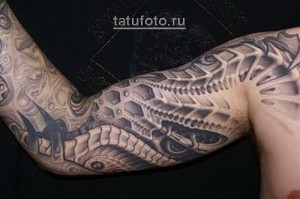 Фото тату биомеханики на руке. Детализированный рисунок, имитирующий механические части под кожей, выполнен в серых тонах.
