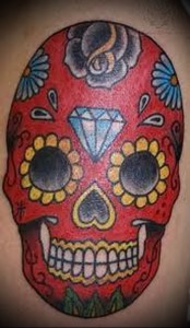 Фото тату: красочный череп в стиле Day of the Dead с розами, бриллиантом и цветами на теле.