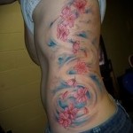 цветочки и голубые разводы (волны - облака) - женская татуировка на боку