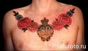 Фото тату: татуировка с изображением красных роз, вензеля и инициалов SR на груди мужчины. Классический стиль, яркие цвета, элегантный дизайн.