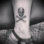череп и кости в татуировка в нижней части ноги девушки