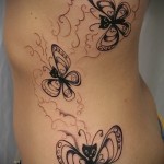 черные бабочки с головами кошек - женская татуировка на боку