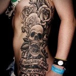 черные розы и череп с надписями - женская татуировка на боку