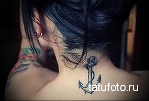 Фото тату: небольшая татуировка якоря на шее девушки. Черно-белый рисунок с четкими контурами и лаконичным дизайном.