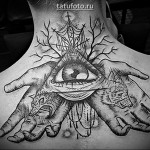 Татуировка глаз в треугольнике на спине девушки