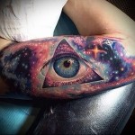 Всевидящее око и космос - цветная татуировка на руке