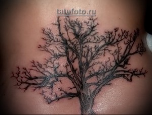 Фото тату дерева с черным стволом и красными ветвями. Изображение выполнено на коже в минималистичном стиле. Эскиз татуировки выглядит необычно и привлекательно.