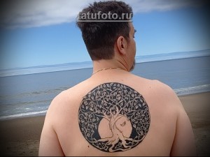 Фото тату: круглая черно-серая татуировка Древа Жизни на спине мужчины, выполненная в кельтском стиле.