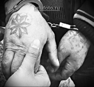 Фотография татуировки в виде звезды на руке, выполненной в черно-белой гамме. Изображение выглядит как традиционная тюремная татуировка.