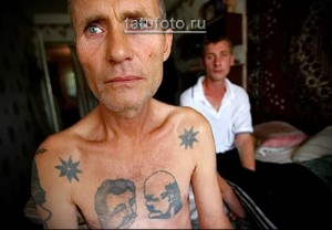 Фотография мужчины с тюремными татуировками на груди, включая портреты Ленина и Сталина, выполненные в черно-белой гамме.