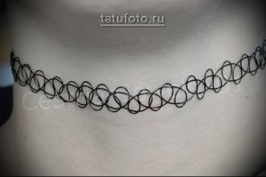 Фото тату черного чокера на шее. Простой и элегантный дизайн татуировки в стиле минимализм. Идеально подходит для тех, кто ценит лаконичность.