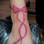 Красный бант и сердечки в татуировке на ногу