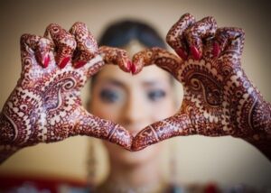 Фото росписи хенной на руках, образующих форму сердца. Изящные узоры и детализированный рисунок.
