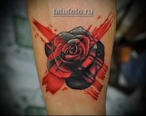 Фото тату на руке: роза, красные брызги, реалистичный стиль, черно-серые тона, символ любви.
