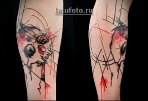 Фото абстрактной татуировки на икре с изображением черепа, выполненного в технике брызг и линий. Современный рисунок татуировки.