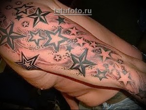 Фото татуировки, покрывающей большую часть руки, с изображением звездного неба. Разнообразные звезды и оттенки серого.