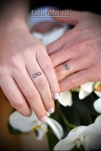 Фото парных татуировок с изображением символа бесконечности на пальцах. Минималистичный дизайн, черные чернила.