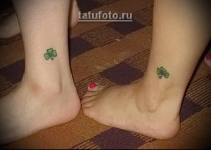 Фото парной татуировки на лодыжках: два маленьких зеленых четырехлистных клевера.