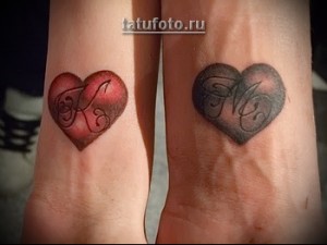 Фото парных татуировок в виде красного и серого сердец с инициалами 'К' и 'М', выполненных на запястьях.