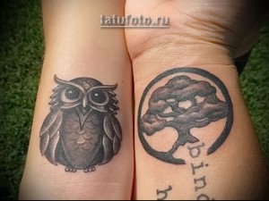 Фото парных татуировок на предплечьях, изображающих сову и дерево в круге. Черно-серый рисунок.