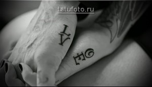 Фото парных татуировок с надписями "Love" и "Hate" на руках. Черно-белый дизайн, готический шрифт.