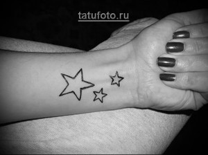 Фото тату с изображением трех маленьких черных звездочек на женском запястье. Простой и элегантный рисунок татуировки.