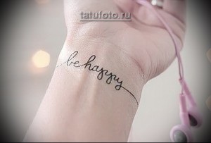 Фото тату: надпись "Be Happy" изящным шрифтом на запястье. Простой и позитивный рисунок татуировки, вдохновляющий на радость.