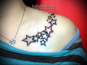 Фото татуировки с изображением нескольких разноцветных звезд, расположенных на ключице. Звезды выполнены в ярких и насыщенных цветах.