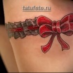 татуировка подвязка для чулков и красный бант на ноге