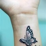 черная бабочка в женской татуировке на руке