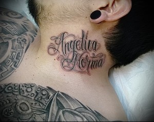 Фото тату надписи 'Angelica Norma' на шее, выполненной в нежном стиле с использованием тонких линий и розовых оттенков. Идеально для тех, кто ищет женственные идеи для тату.