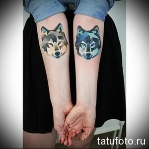 Фото парных татуировок с изображением волчьих голов на голенях. Геометрический стиль с использованием синих и серых оттенков.