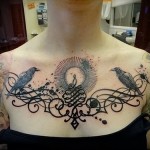 тату ворон в узорах в женской татуировке на груди