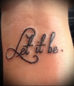 Фотография татуировки с надписью 'Let it be' на запястье. Простой, но глубокий смысл, выраженный в изящном шрифте.