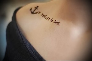 Фотография татуировки на лопатке с изображением якоря и надписи 'I Refuse to Sink'. Стильный и вдохновляющий рисунок, символизирующий силу духа и непоколебимость.