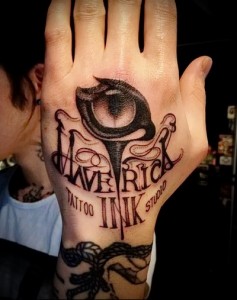 Фотография татуировки на ладони с изображением тату-машинки и надписью 'Maverick Ink Studio'. Стильный и оригинальный рисунок для любителей татуировок.