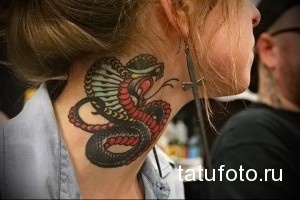 Фото тату кобры на шее женщины. Рисунок выполнен в стиле олдскул с использованием ярких цветов: красного, черного и зеленого. Детализированный эскиз тату.