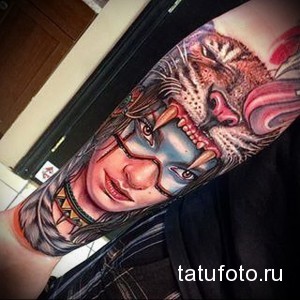 Фото тату на руке: девушка, лицо которой переходит в голову тигра. Яркие цвета, детализированная проработка и динамичная композиция.