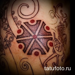Фото татуировки скандинавского символа на руке, выполненной в стиле blackwork с использованием плотных черных заливок и геометрических узоров.