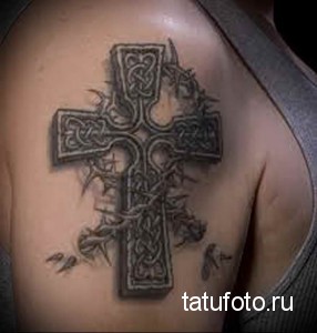 Фото татуировки кельтского креста с терновым венцом на плече. Черно-серый рисунок татуировки с детальной проработкой узоров и теней.